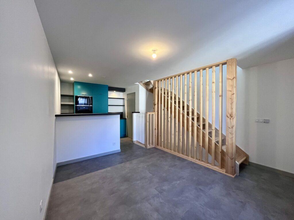 Pièce de vie et escalier bois d'un T2 créé dans une grange à Chabanière