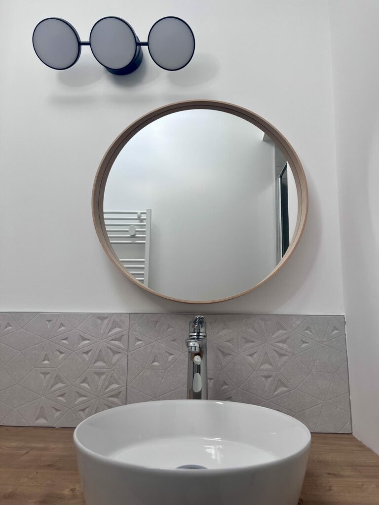 Vasque et miroir rond d'une salle d'eau à Chabanière